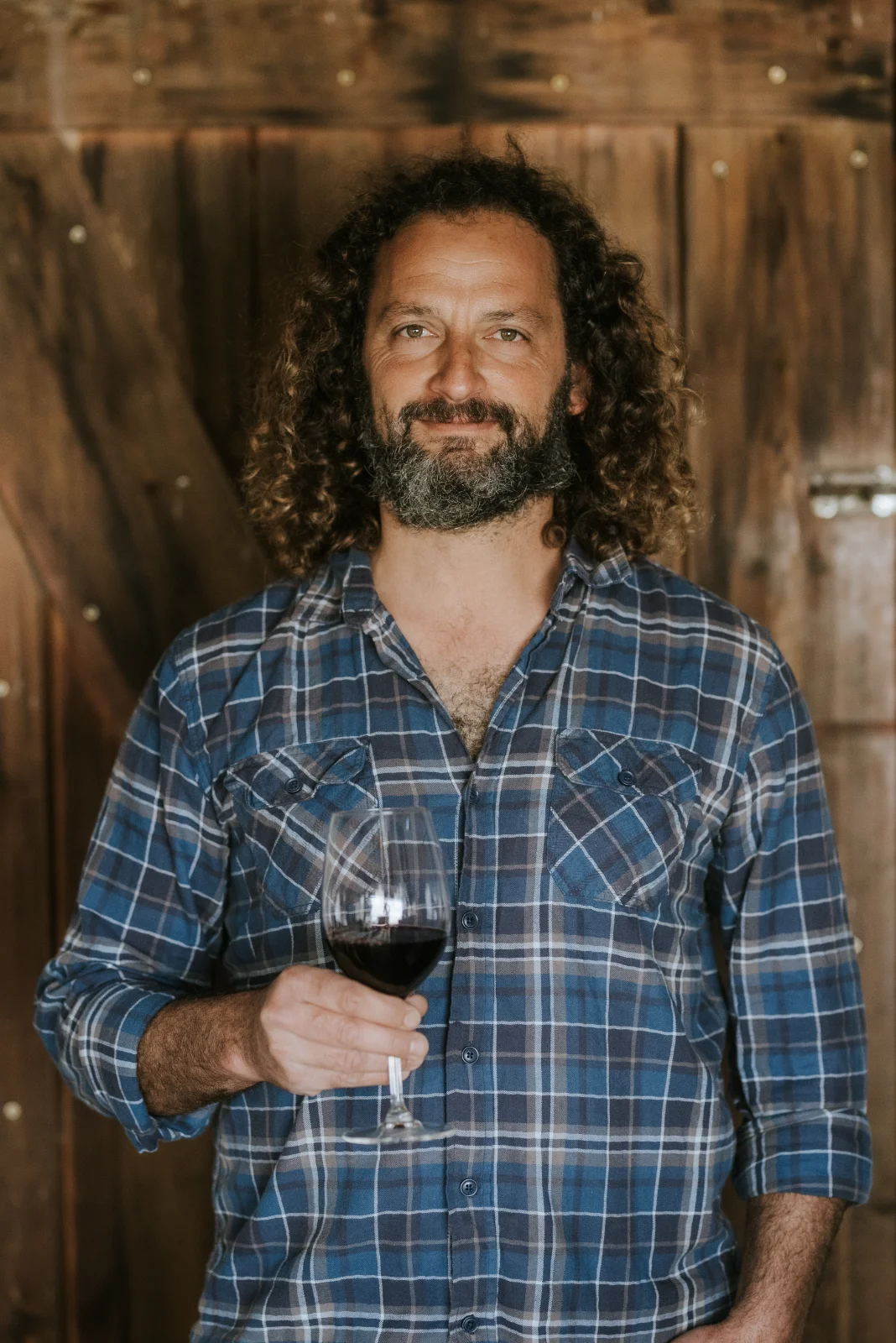 בעל יקב תום מוזג יין אדום לכוס – צילום באווירה כפרית